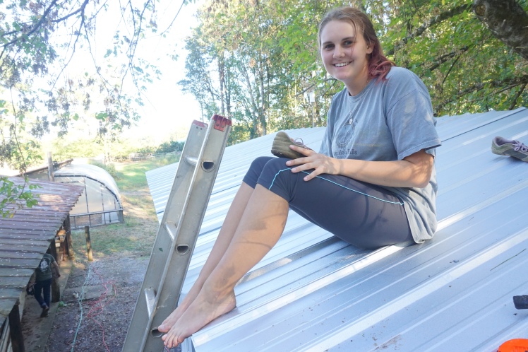 A smiling Alyssa after spending a couple hours screwing the metal roof onto the top of the house